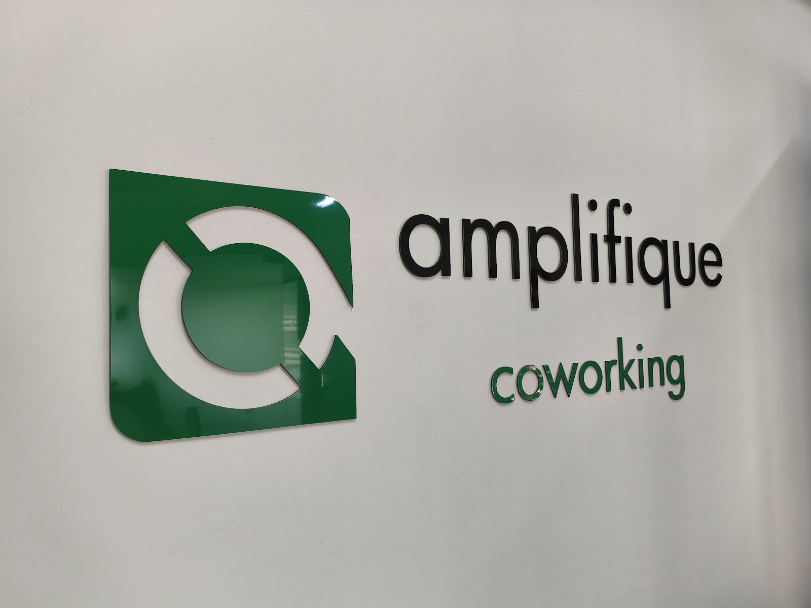 Parede com o logo do Amplifique Coworking na recepção da unidade República